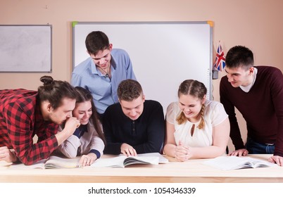 Young People Studying With Books On White Desk. Beautiful Girls And Guys Working Together Wearing Casual Clothes. 