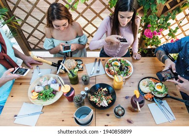 Young people taking food pictures with mobile smartphone to share on social media while having healthy meal in bar restaurant - Youth generation z and technology concept - Shutterstock ID 1940858899