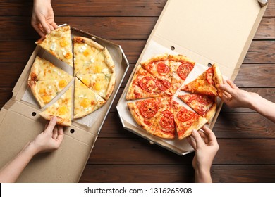 Young people taking slices of hot cheese pizzas from cardboard boxes at table, top view. Food delivery service - Powered by Shutterstock