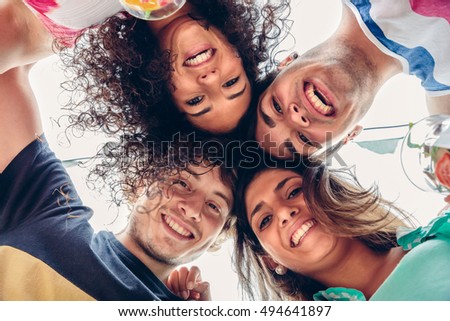 Young happy people with their heads together having fun in summer party