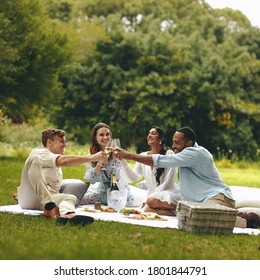 Young people toasting champagne while on a picnic. Young group of friends sitting at park and having champagne. - Powered by Shutterstock