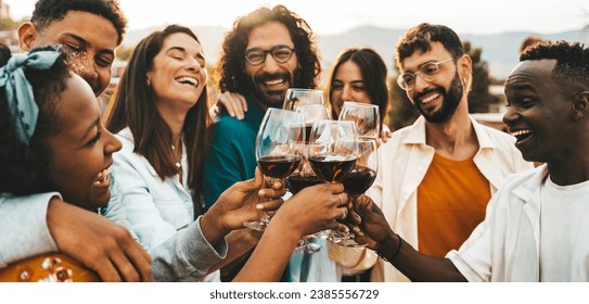 Young people toasting red wine glasses at farm house vineyard countryside - Happy friends enjoying happy hour at winery bar restaurant - Guys and girls having rooftop house party together - Powered by Shutterstock