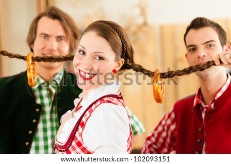 Young people in traditional Bavarian Tracht in restaurant or pub having fun and making jokes