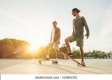 Young people training with longboard with back sun light- Skaters friends outdoor in urban city with skateboards  -Extreme sport and friendship concept - Focus on right man's feet - Warm filter - Powered by Shutterstock