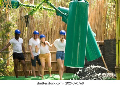 Young People Try To Walk The Wet Log In The Theme Park. High Quality Photo