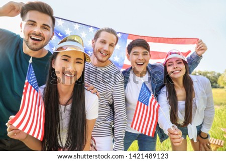 Young people with USA flags outdoors. Independence Day celebration