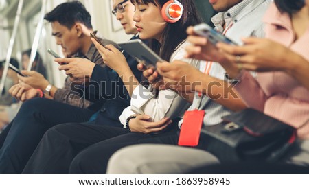 Young people using mobile phone in public underground train . Urban city lifestyle and commuting in Asia concept .