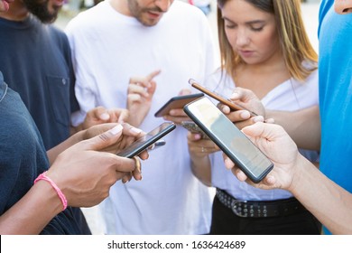 Young people using smartphones while standing on street. Thoughtful friends using digital devices on city square. Communication, technology concept