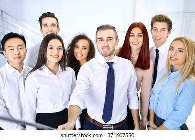 Young People Using Stick For Group Photo In Office