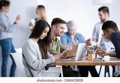 Young people of various descent sitting in an office, working on a laptop and mobile phone - Shutterstock ID 1060433828