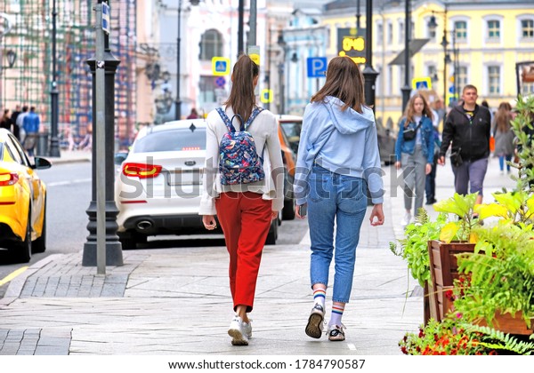 young people walking along\
street in Moscow city historic downtown against car taxi traffic on\
background. Authentic lifestyle in Moscow Russia on July\
2020