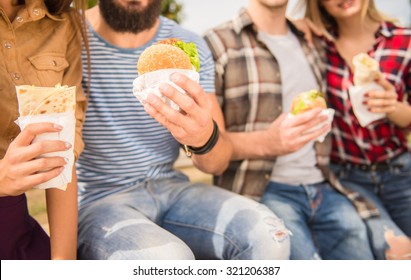 Young people walking outdoors. Sitting in the park and eat fast food