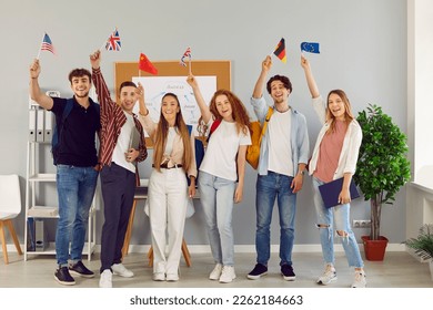 Young people who take part in university exchange program meet and make friends of different nationalities. Happy cheerful joyful international students standing together, holding up flags and smiling - Shutterstock ID 2262184663