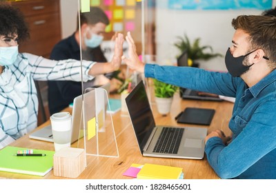 Young People Working Inside A Coworking Behind Safety Plexiglass During Coronavirus Outbreak - Focus On Right Man Face