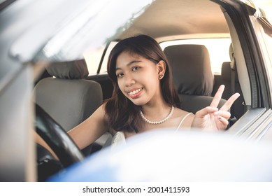 A Young And Peppy Filipina Girl Enjoys Driving Her New Hatchback Car. Windows Rolled Down.