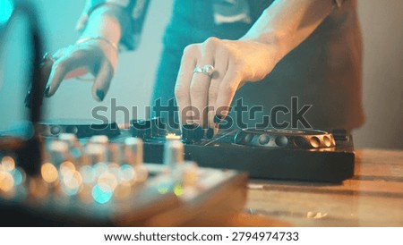 Young performer using DJ electronics and headset to mix techno music and play remix songs on turntables, having fun at nightclub.