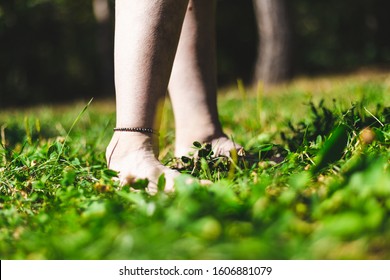 Young person with ankle bracelet walking relaxed barefoot in grass on a summer day - Fun and pleasant activity in nature on a beautiful green lawn on a bright sunny day - Shutterstock ID 1606881079