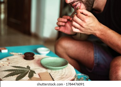 Young person preparing marijuana joint while rolling a pipe - Smooking cannabis weed concept - Main focus on left hand