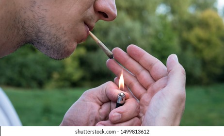 The Young Person Smoking Medical Marijuana Joint Outdoors. The Young Man Smoke Cannabis Blunt, Close-up. Cannabis Is A Concept Of Herbal Medicine.