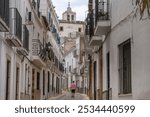 Young person in sportswear walking through the narrow medieval stone streets of alburquerque with balconies in their windows. Extremadura. Spain. 