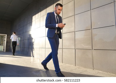 Young perspective male men, students,go to meet each other, greet one another, shake hands, talking on phone, stop and talk, walk fast step, hurry, running late on background of wall of business - Powered by Shutterstock