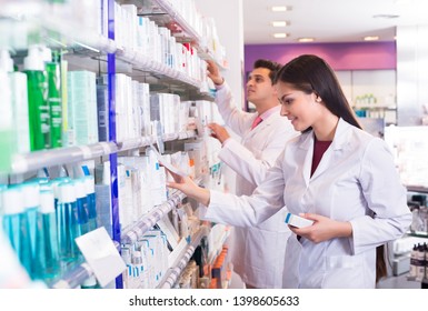 Young Pharmacist And Pharmacy Technician Posing In Drugstore