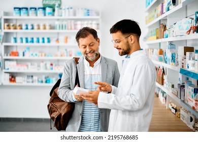 Young pharmacist talking to male customer in a drugstore. Focus is on customer. 