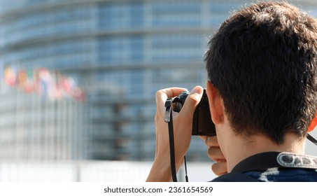 Young photogapher with digital camer  during a travel  and many flags in background