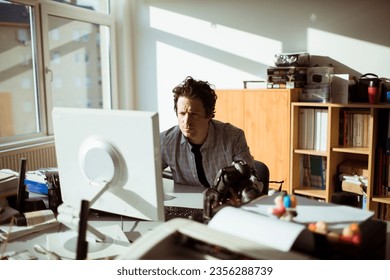 Young photographer going through his camera at his desk in the office office - Powered by Shutterstock