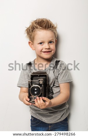 Young photographer. Little boy hold vintage camera. Studio portrait over white background