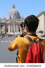 Young photographer in Rome in summer with camera and the Basilica of Saint Peter in Background