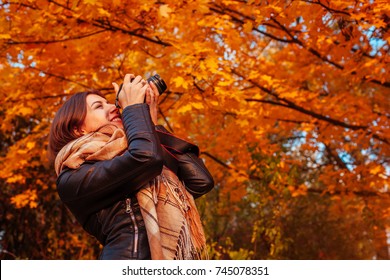 Young photographer takes pictures of autumn forest at sunset