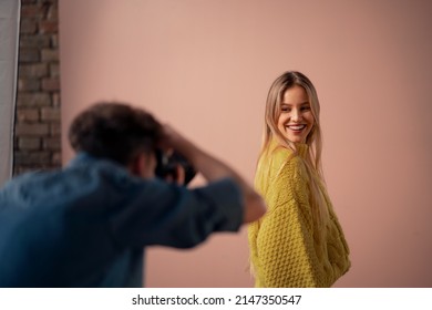 Young photographer taking picures of model, backstage of photoshooting in studio.