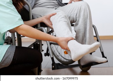 Young physiotherapist exercising with elder disabled person