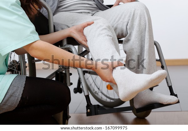 Young physiotherapist exercising with elder\
disabled person