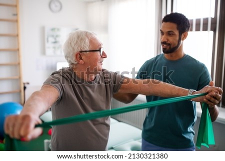 Young physiotherapist exercising with senior patient in a physic room
