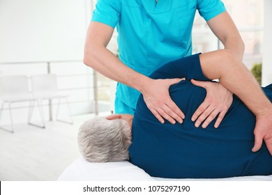 Young physiotherapist working with senior patient in clinic
