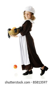 A young Pilgrim girl carrying a basket full of fruit for the first Thanksgiving feast.  One apple has fallen.  All on a white background.