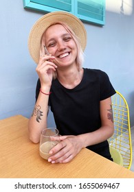 Young Pink Hair Girl In A Hat Smoking Joint And Have Coffee Outside At Sunny Day.