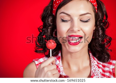 Young pin-up girl with lollipop on red background