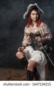 Young pirate female with long red hair. Woman is wearing a black corset bustier, tricorn hat , gun belt and armed with a pistol and sword.