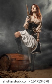 Young pirate female with long red hair. Woman is wearing a black corset bustier, tricorn hat , gun belt and armed with a pistol and sword.