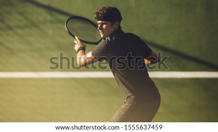 Young player playing tennis on hard court. Professional tennis player hitting a forehand during a match.