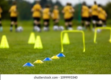 Young Players at the Football Training Session. Young Footballers Training Run with Ball DrillsSoccer Balls, Pylons, Cones, Marks and Training Hurdles on Grass Pitch. Youth Soccer Pre-season Training
