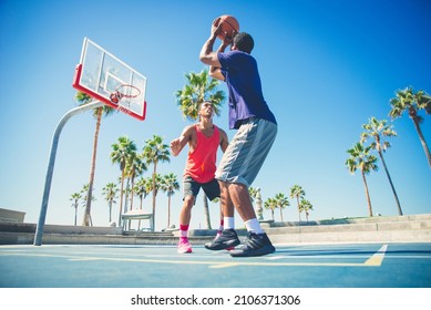 Young players playing basketball at the court in venice beach, California. Professional street ballers having fun performing tricks and huge slam dunks