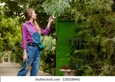 Young pleasant woman with hoe enjoying spending time in the garden with wonderful plants. close up photo. copy space