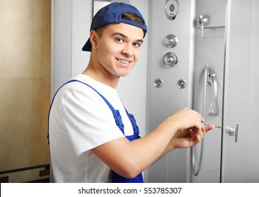 Young Plumber Fixing Shower Cabin