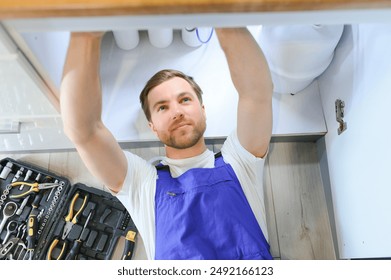 Young plumber or technician installing or repairing system of water filtration. - Powered by Shutterstock