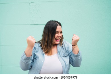 Young plus size woman celebrating victory.