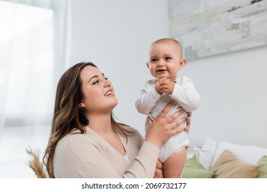 Young Plus Size Woman Holding Smiling Baby Daughter At Home